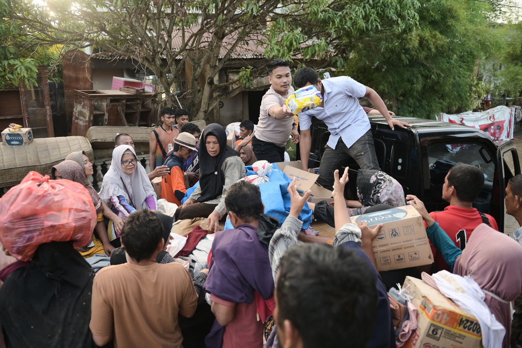 Volunteers distribute relief goods to survivors at a village affected by flash flood in Pidie Jaya, Aceh province, Indonesia, Tuesday, Dec. 2, 2025. (AP Photo/Reza Saifullah)