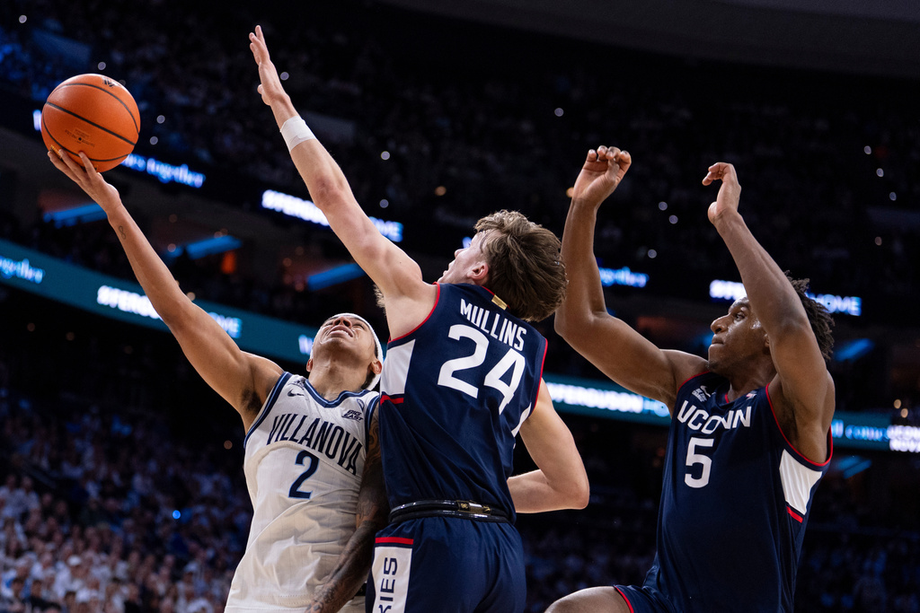 Villanova's Bryce Lindsay, left, goes up to shoot against UConn's Braylon Mullins, center, and Tarris Reed Jr., right, during the first half of an NCAA college basketball game, Saturday, Feb. 21, 2026, in Philadelphia. (AP Photo/Chris Szagola)