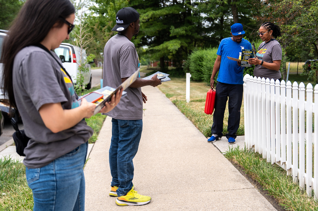Darci McConnell, communications director, right, talks to a voter as Madison Steigerwald, canvas lead, left, Kenneth Brooks, canvasser, second from right, watch, while canvassing with Michigan United Action for candidates including Abdul El-Sayed, a progressive candidate in the Democratic primary for U.S. Senate in Michigan, Saturday, Aug. 1, 2026, in Detroit. (AP Photo/Julia Demaree Nikhinson)