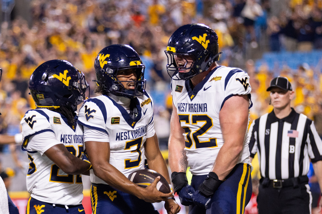 West Virginia quarterback Michael Hawkins Jr. (3) celebrates with offensive lineman Nick Krahe (52) after a touchdown in the first half against Virginia in an NCAA college football game Saturday, Sept. 19, 2026, in Charlotte, N.C. (AP Photo/Scott Kinser)