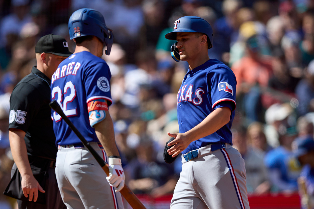 Texas Rangers' Corey Seager, right, is greeted by Evan Carter, front left, while scoring against the Seattle Mariners during the seventh inning in a baseball game Sunday, April 19, 2026, in Seattle. (AP Photo/John Froschauer)