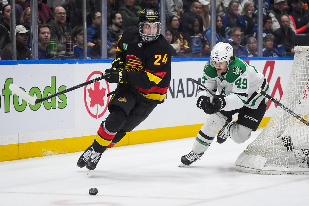 Vancouver Canucks' Zeev Buium (24) skates after the puck while being chased by Dallas Stars' Justin Hryckowian (49) during the second period of an NHL hockey game in Vancouver, British Columbia, Monday, March 2, 2026. (Darryl Dyck/The Canadian Press via AP)
