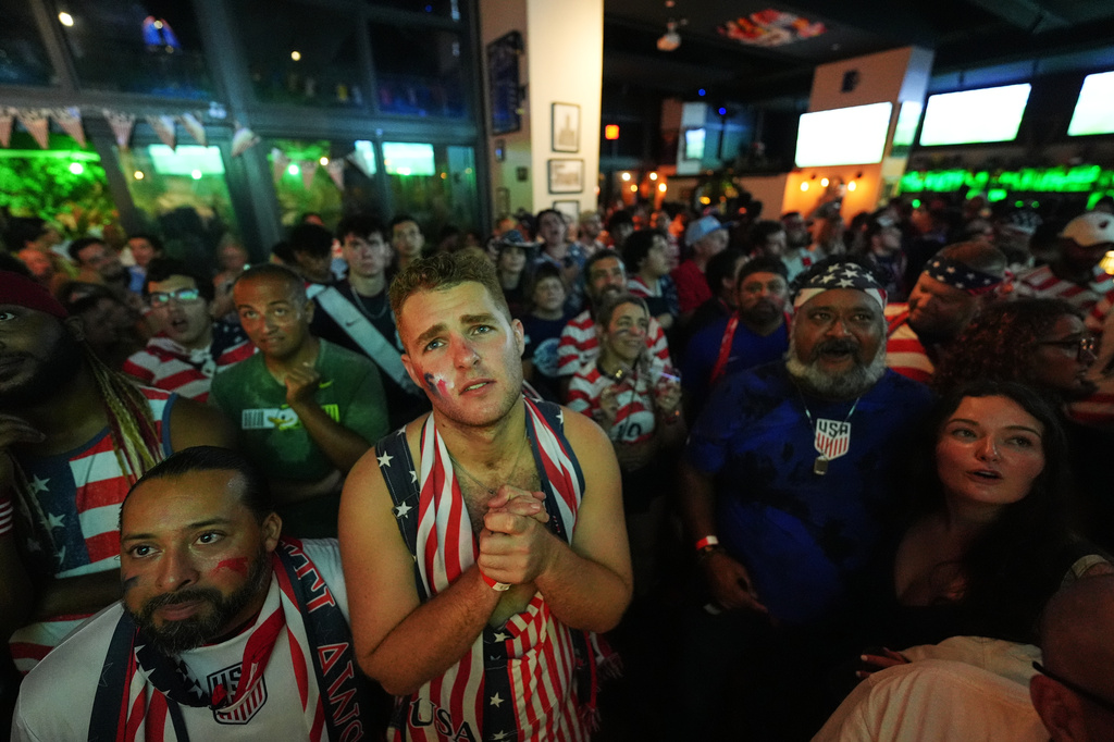 Tommy Floeter, center, and other United States fans with the American Outlaws supporters group react at The Leinster Irish pub in Miami as they watch a live broadcast of a World Cup round of 16 soccer match between the United States and Belgium, Monday, July 6, 2026. (AP Photo/Rebecca Blackwell)