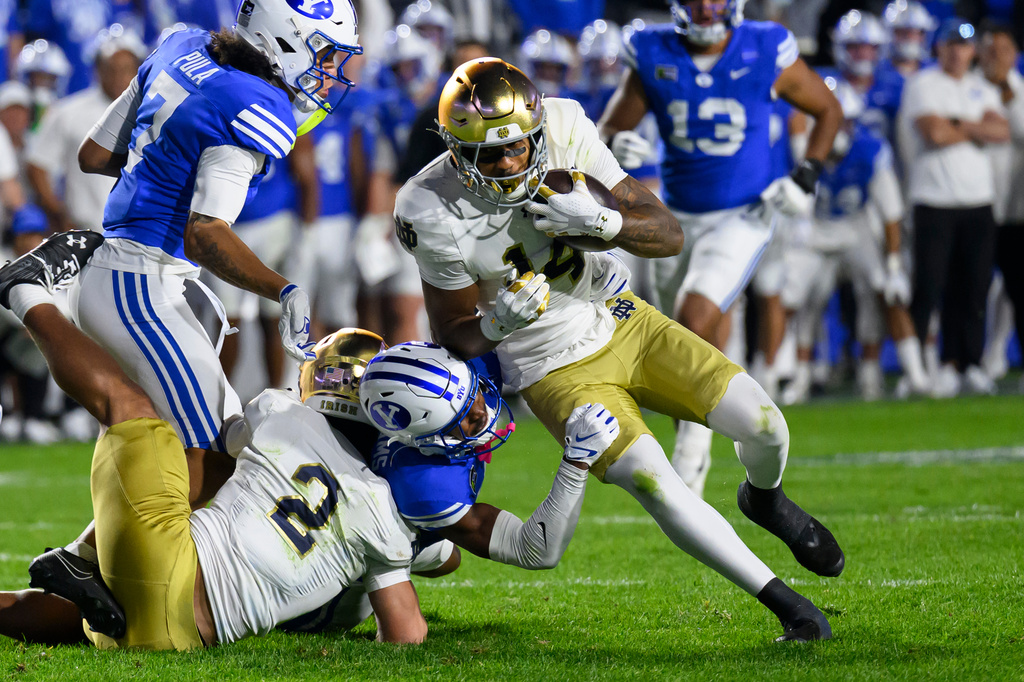 BYU linebacker Isaiah Glasker, bottom center, makes the tackle on Notre Dame wide receiver Micah Gilbert, center right, during the second half of an NCAA college football game, Saturday, Oct. 17, 2026, in Provo, Utah. (AP Photo/Tyler Tate)