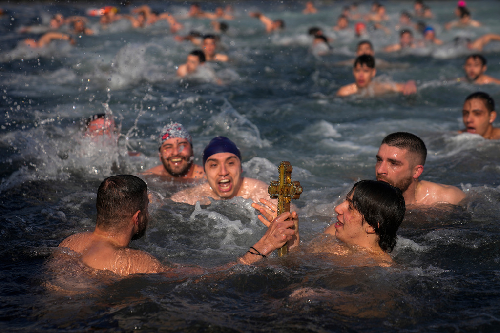 Greek Orthodox faithful hold up a wooden crucifix after it was retrieved in the Golden Horn during the Epiphany ceremony, in Istanbul, Turkey, Jan. 6, 2025. (AP Photo/Khalil Hamra, File)