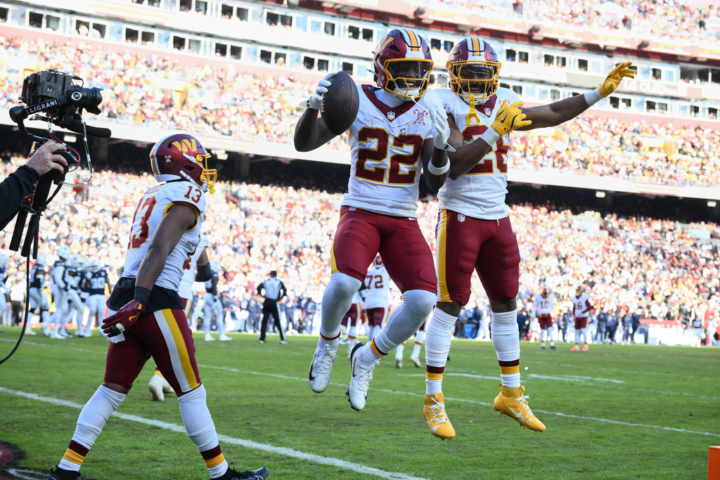 Washington Commanders running back Jacory Croskey-Merritt (22) is congratulated by teammates running back Jeremy McNichols and wide receiver Treylon Burks (13) after scoring during the first half an NFL football game against the Dallas Cowboys Thursday, Dec. 25, 2025, in Landover, Md. (AP Photo/Nick Wass)