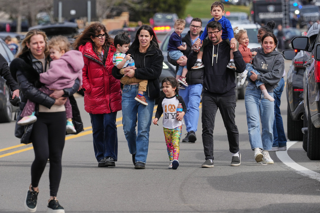 Law enforcement escort families with children away from the Temple Israel synagogue Thursday, March 12, 2026, in West Bloomfield Township, Mich. (AP Photo/Paul Sancya)
