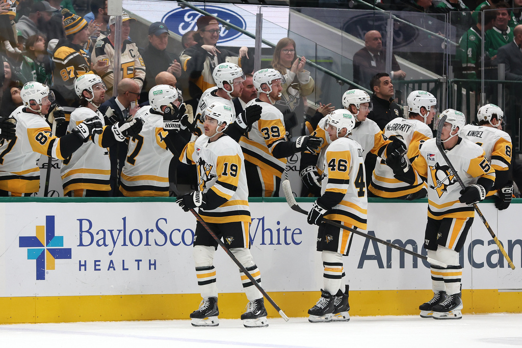 Pittsburgh Penguins center Connor Dewar (19) is congratulated by teammates on his bench after scoring a goal against the Dallas Stars during the first period of an NHL hockey game Sunday, Dec. 7, 2025, in Dallas. (AP Photo/Sam Hodde)