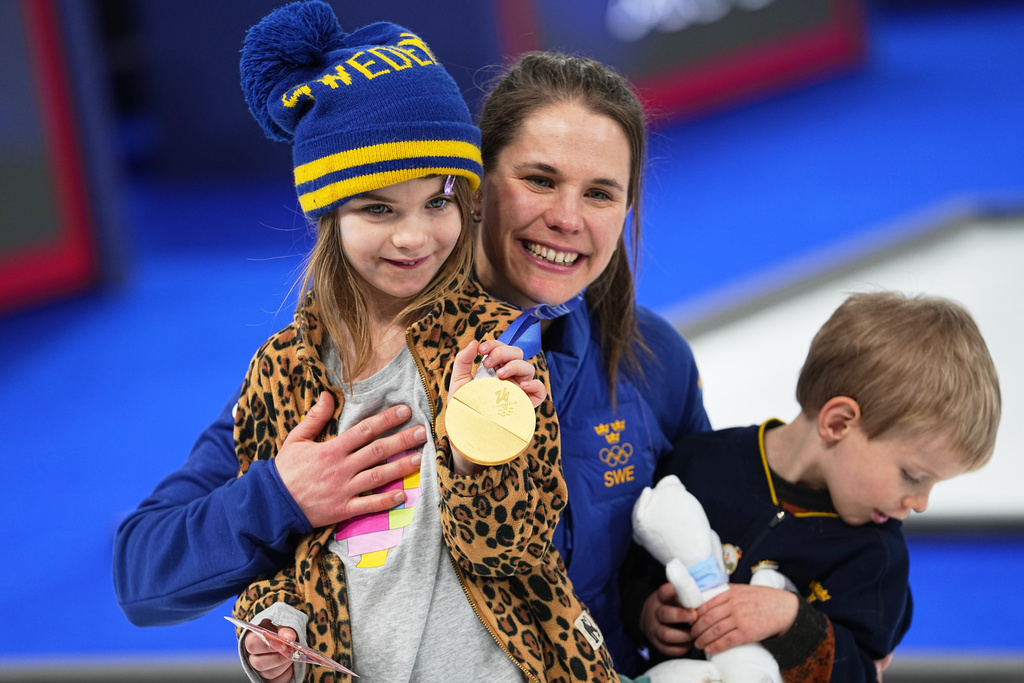 Sweden's Anna Hasselborg poses with her children showing the gold medal of the women's curling, at the 2026 Winter Olympics, in Cortina d'Ampezzo, Italy, Sunday, Feb. 22, 2026. (AP Photo/Fatima Shbair)