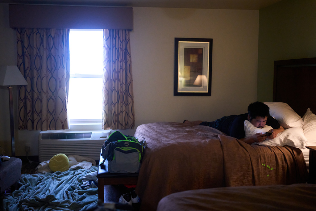 Peter "Joe" Paul looks at his phone in his temporary hotel housing in Anchorage, Alaska, Wednesday, Oct. 29, 2025, after his family lost their home and were displaced from the village of Kipnuk by Typhoon Halong. (AP Photo/Lindsey Wasson)
