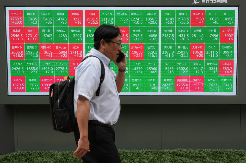 A man walks past a monitor showing stock prices of companies on the Tokyo Stock Exchange in Tokyo, Tuesday, June 23, 2026. (AP Photo/Hiro Komae)