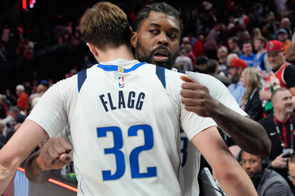 Dallas Mavericks forward Cooper Flagg (32) hugs forward Naji Marshall, right, after an NBA basketball game against the Portland Trail Blazers, Friday, March 27, 2026, in Portland, Ore. (AP Photo/Jenny Kane)