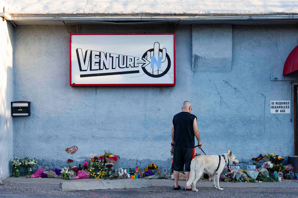 A passerby looks at a growing memorial outside the Venture-N bar in Tucson, Ariz., Tuesday, Sept. 1, 2026, for Vincent Anthony Siquieros and Cameron Davis Capara, who were fatally shot in the parking lot of the gay bar shortly after midnight on Monday. (AP Photo/Rebecca Noble)
