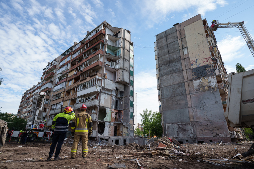 Rescue workers stand in the yard of an apartment building heavily damaged after a Russian strike on residential neighbourhood in Kyiv, Ukraine, on Friday, May 15, 2026. (AP Photo/Evgeniy Maloletka)