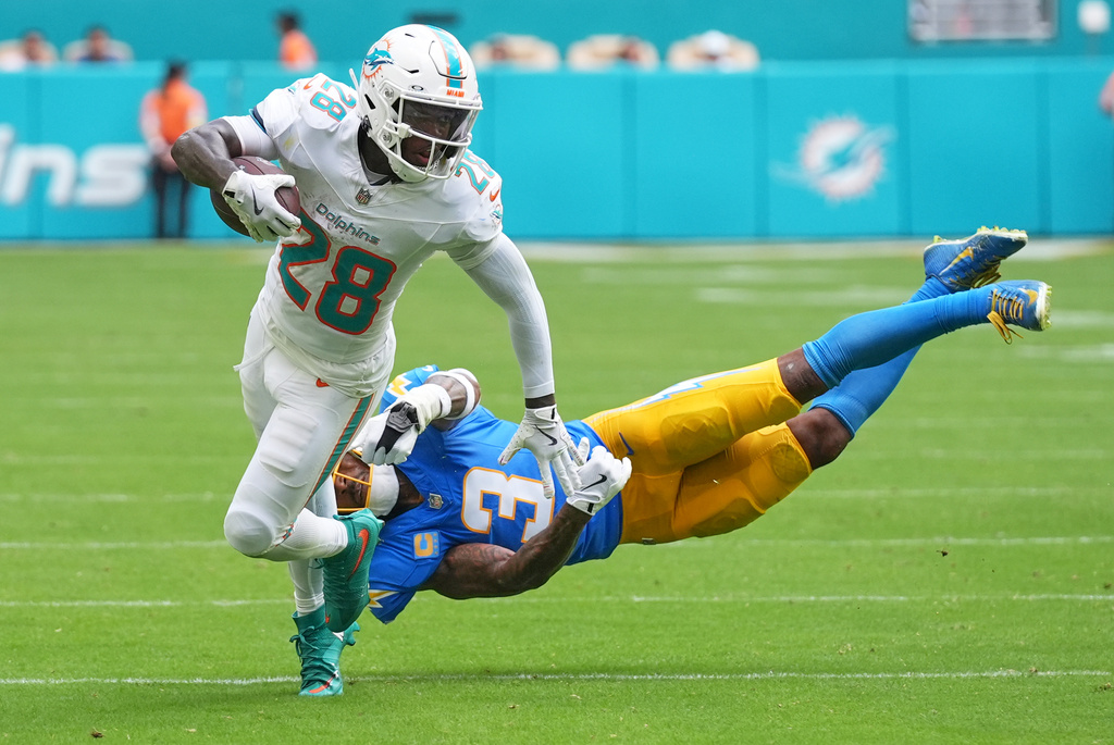 Miami Dolphins running back De'Von Achane, left, breaks free from Los Angeles Chargers safety Derwin James Jr. (3) during the first half of an NFL football game Sunday, Oct. 12, 2025, in Miami Gardens, Fla. (AP Photo/Lynne Sladky)