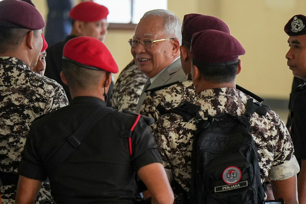 Former Malaysian Prime Minister Najib Razak, center, is escorted by prison officers on his arrival at the Kuala Lumpur High Court Complex, in Kuala Lumpur, Malaysia, Monday, Dec. 22, 2025. (AP Photo/Azneal Ishak)