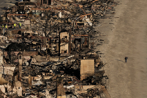 FILE - A person walks on the beach next to homes damaged by the Palisades Fire, Jan. 16, 2025 in Malibu, Calif. (AP Photo/Jae C. Hong, file) FILE - A person walks on the beach next to homes damaged by the Palisades Fire, Jan. 16, 2025 in Malibu, Calif. (AP Photo/Jae C. Hong, file)
