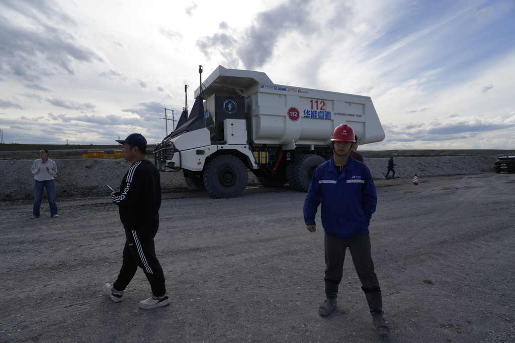Workers walk past an autonomous mining truck in the Huaneng Yimin open-pit coal mine in Hulunbuir in northern China's Inner Mongolia province China, Monday, Sept. 15, 2025. (AP Photo/Ng Han Guan)