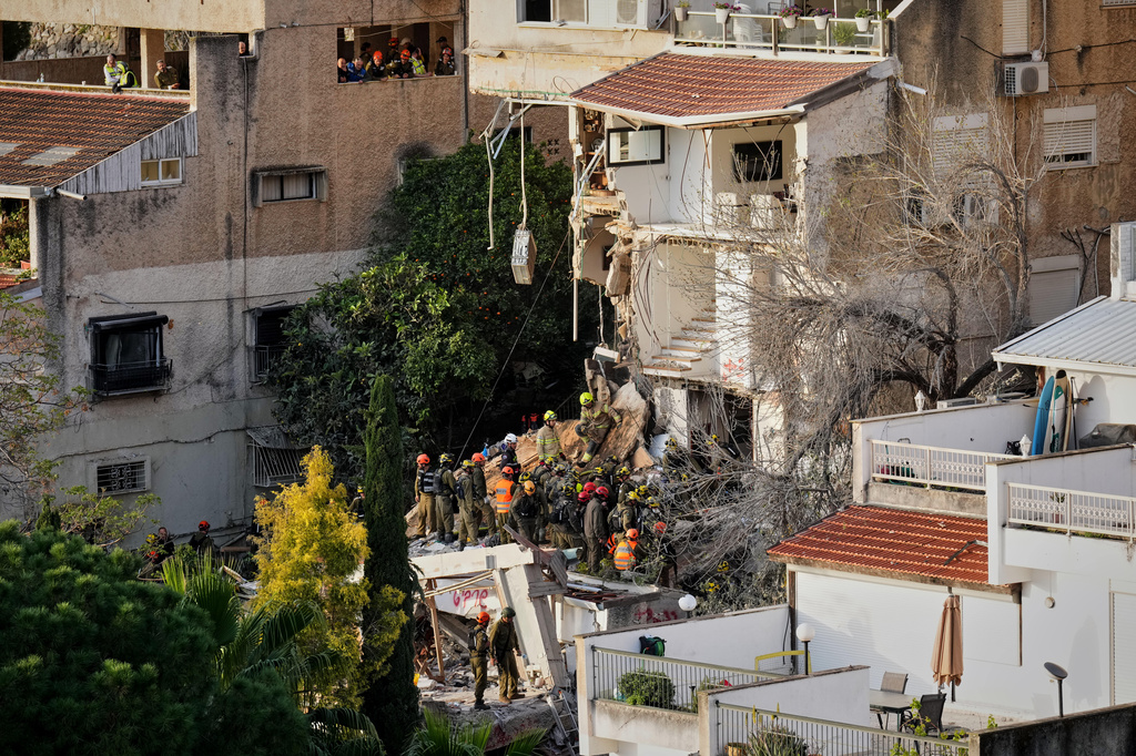 Israeli rescue teams search for missing people amid the rubble of a residential building a day after it was struck by an Iranian missile in Haifa, Israel, Monday, April 6, 2026. (AP Photo/Ariel Schalit)