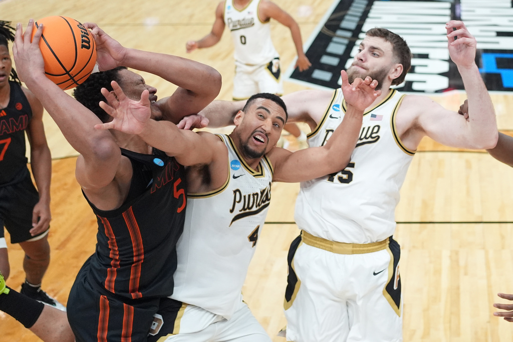 Miami's Malik Reneau (5) heads to the basket as Purdue's Trey Kaufman-Renn (4) and Oscar Cluff, right, defend during the first half in the second round of the NCAA college basketball tournament, Sunday, March 22, 2026, in St. Louis. (AP Photo/Jeff Roberson)
