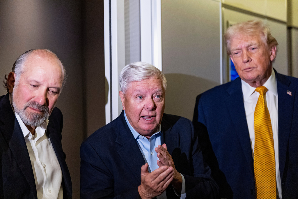 President Donald Trump, accompanied by Commerce Secretary Howard Lutnick, left, and Sen. Lindsey Graham, R-S.C., speaks with reporters while in flight on Air Force One, Sunday, Jan. 4, 2026, as returning to Joint Base Andrews, Md. (AP Photo/Alex Brandon)
