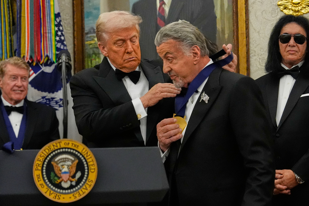 President Donald Trump, left, presents Sylvester Stallone with his Kennedy Center Honors medal in the Oval Office of the White House, Saturday, Dec. 6, 2025, in Washington. (AP Photo/Julia Demaree Nikhinson)