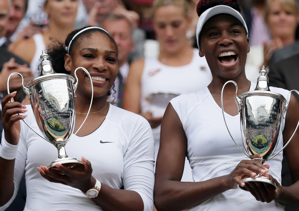 FILE -Serena Williams, left, and Venus Williams of the U.S hold their trophies after winning the women's doubles final against Yaroslava Shvedova of Kazahkstan and Timea Babos of Hungary on day thirteen of the Wimbledon Tennis Championships in London, July 9, 2016. (AP Photo/Tim Ireland, File)