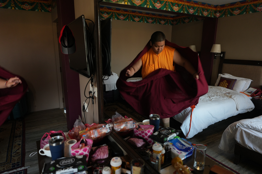 U.S.-born Buddhist lama Jalue Dorje puts on his monastic robes at his hotel room to start his day before attending a series of rituals and prayers at Shechen Monastery in Kathmandu, Nepal, on Saturday, April 11, 2026. (AP Photo/Luis Andres Henao)