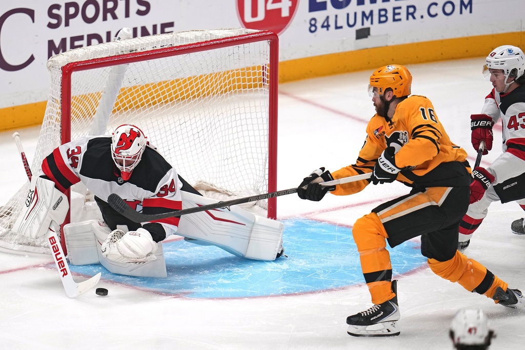 New Jersey Devils goaltender Jake Allen (34) blocks a shot by Pittsburgh Penguins' Justin Brazeau (16) with Luke Hughes (43) defending during the first period of an NHL hockey game in Pittsburgh, Thursday, Jan. 8, 2026. (AP Photo/Gene J. Puskar)