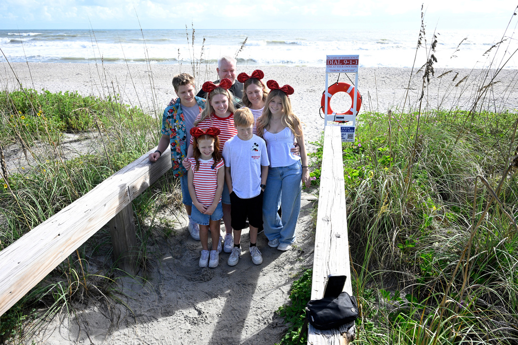 Brian and Carrie Archibald, of Gilbert, Ariz., make a selfie photo with their children at Blockhouse Beach before heading out on a Disney cruise as Tropical Storm Imelda passes offshore, kicking up the surf, Monday, Sept. 29, 2025, at Patrick Space Force Base, Fla. (AP Photo/Phelan M. Ebenhack)