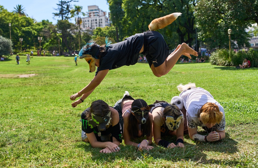 A youth jumps over other therians, people who say they identify as non-human animals, during a gathering in a square in Buenos Aires, Argentina, Sunday, Feb. 22, 2026. (AP Photo/Rodrigo Abd)