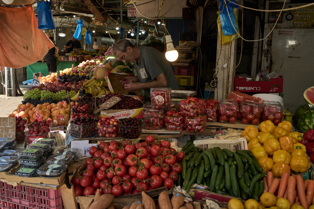 A vendor checks the fruits on his stand at a local street market following air raid sirens warning of incoming Iranian missiles in Haifa, northern Israel, Monday, June 8, 2026. (AP Photo/Leo Correa)