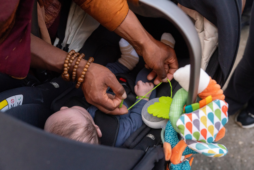 A Buddhist monk ties a prayer bracelet around the wrist of Josey Lee, 2-months-old, during the, "Walk For Peace," Thursday, Jan. 8, 2026, in Saluda, S.C. (AP Photo/Allison Joyce)