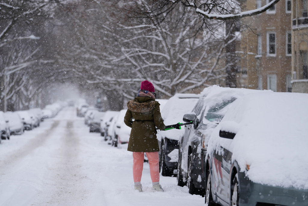 A person cleans the snow from a car during a snowy day in Chicago, Sunday, Jan. 25, 2026. (AP Photo/Nam Y. Huh)