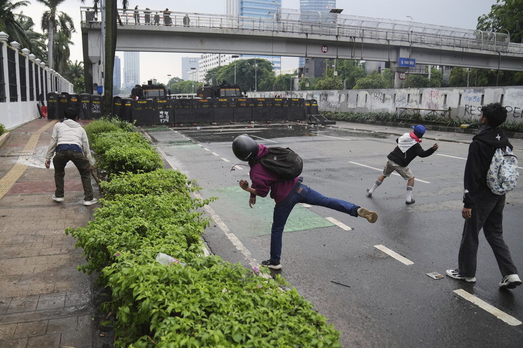 Protesters throw rocks at the police during a protest against lavish allowances given to parliament members, outside the parliament in Jakarta, Indonesia, Sunday, Aug. 31, 2025. (AP Photo/Dita Alangkara)