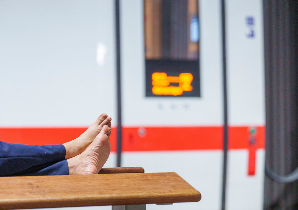 A commuter stretches out on a bench at Frankfurt's main station, Tuesday, June 23, 2026, after a communications system failure forced Germany's railway system to suspend train service. (Andreas Arnold/dpa via AP)