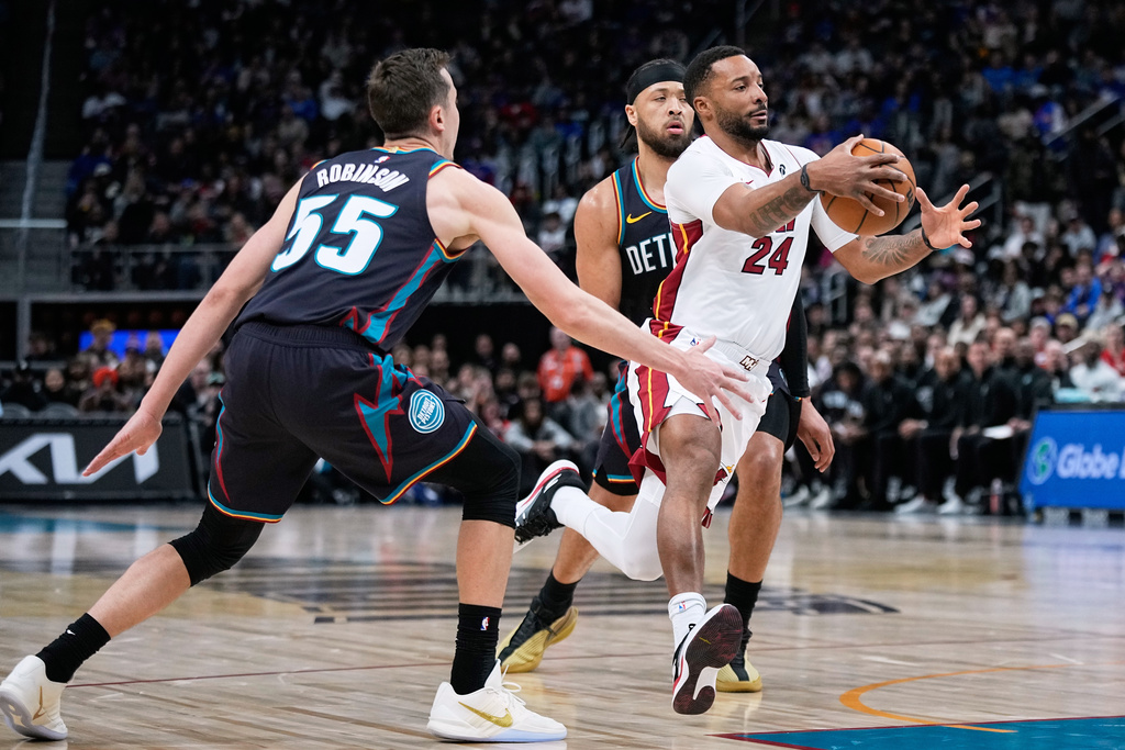 Miami Heat guard Norman Powell, right, drives past Detroit Pistons forward Duncan Robinson, left, and guard Cade Cunningham during the first half of an NBA basketball game, Thursday, Jan. 1, 2026, in Detroit. (AP Photo/Ryan Sun)