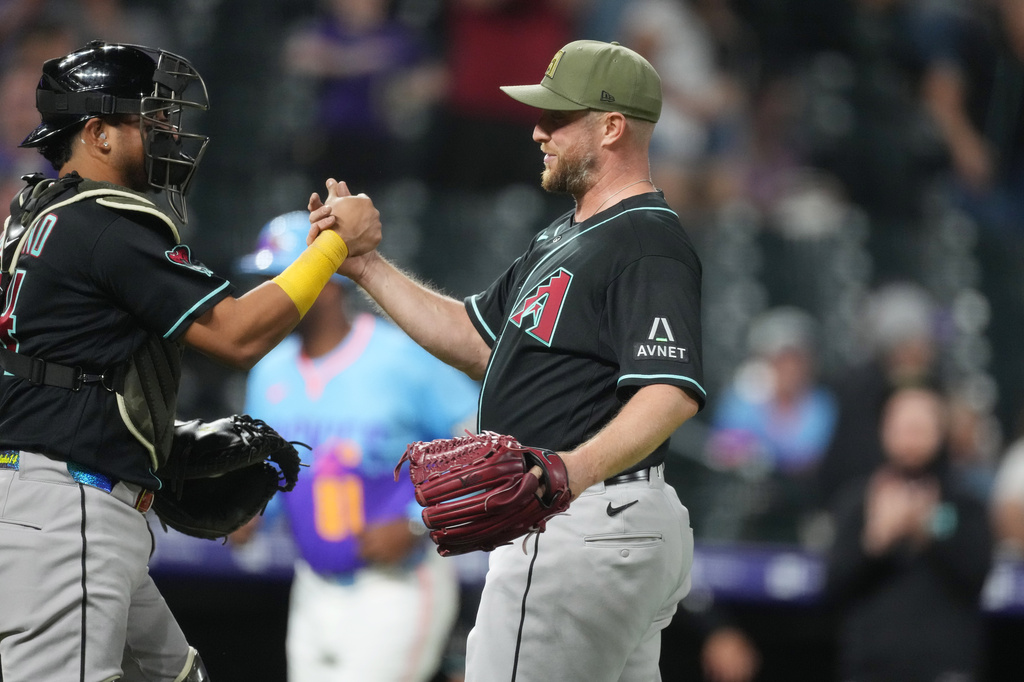 Arizona Diamondbacks catcher Gabriel Moreno, left, congratulates starting pitcher Merrill Kelly, right, after Kelly threw a complete baseball game to defeat the Colorado Rockies, Friday, May 15, 2026, in Denver. (AP Photo/David Zalubowski)