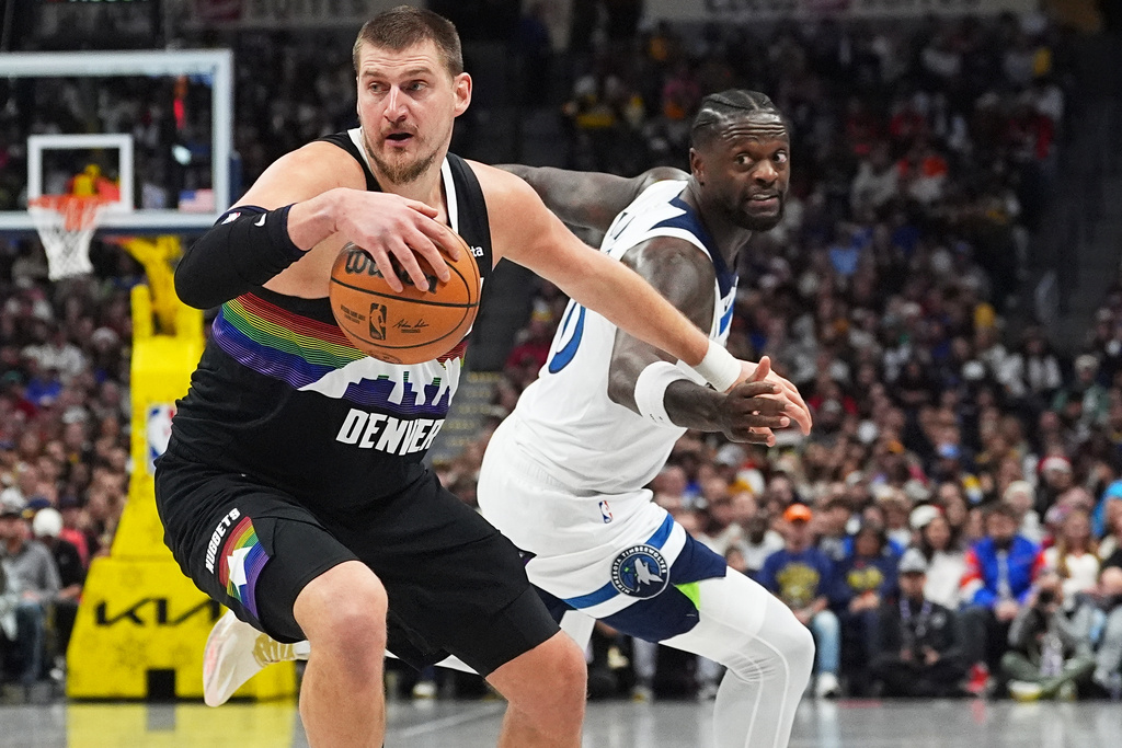 Denver Nuggets center Nikola Jokić, front, dribbles past Minnesota Timberwolves center Julius Randle in the first half of an NBA basketball game, Thursday, Dec. 25, 2025, in Denver. (AP Photo/David Zalubowski)