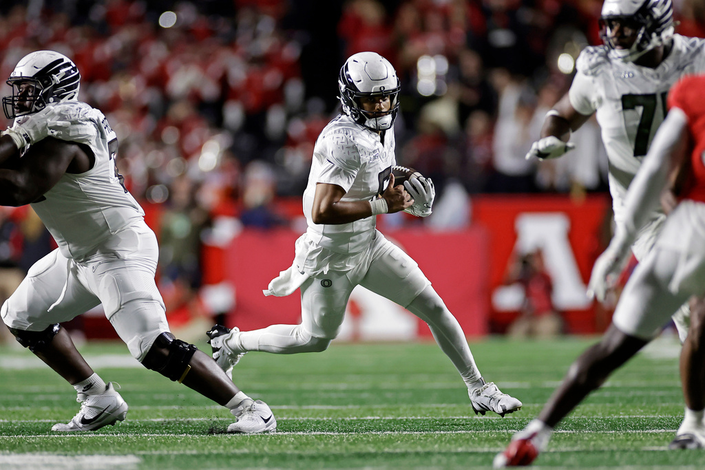 Oregon quarterback Dante Moore, center, runs with the ball during the first half of an NCAA college football game against Rutgers, Saturday, Oct. 18, 2025, in Piscataway, N.J. (AP Photo/Adam Hunger)
