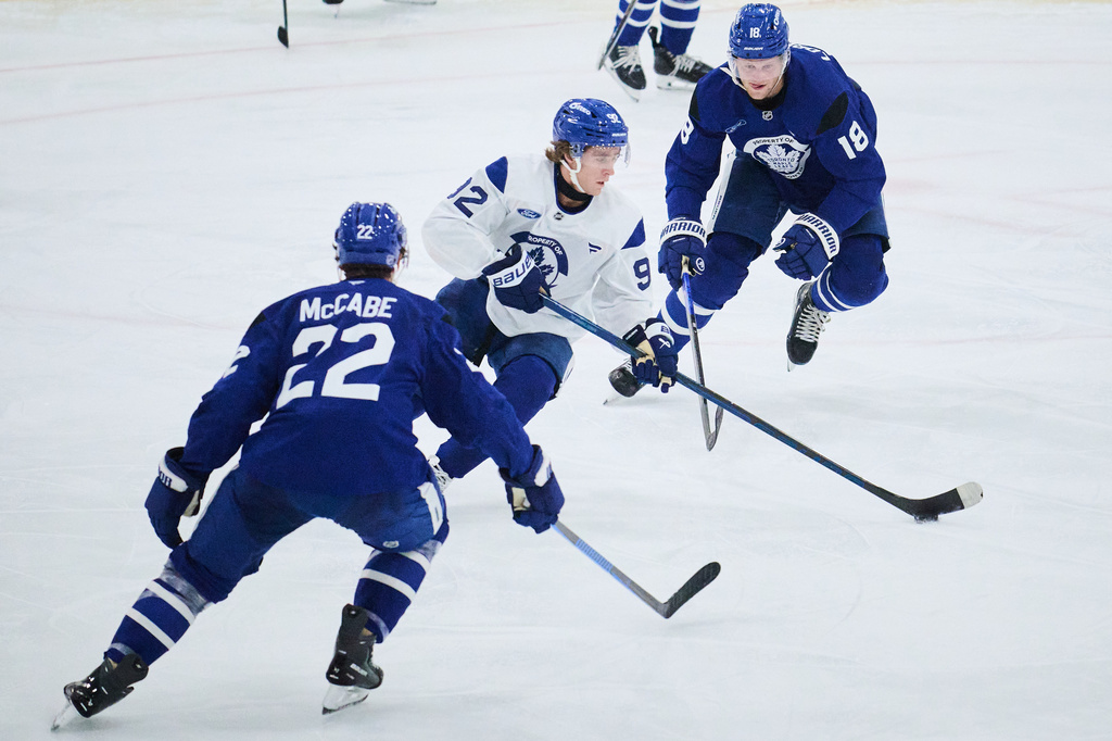 Toronto Maple Leafs' Gavin McKenna, center, keeps the puck from Jake McCabe (22) and Steven Lorentz (18) during the NHL hockey team's training camp in Toronto, Thursday, Sept. 17, 2026. (Sammy Kogan/The Canadian Press via AP)