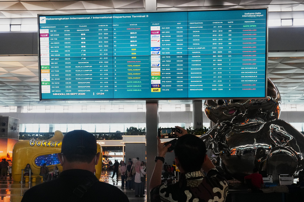 Travelers walk past an information board showing disrupted flights at Soekarno-Hatta International Airport in Tangerang, Indonesia, Sunday, Sept. 6, 2026. (AP Photo/Tatan Syuflana)