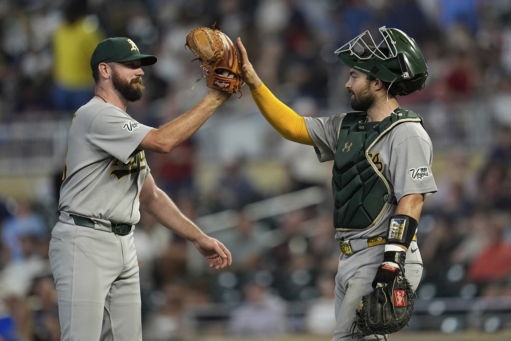 Athletics relief pitcher Hogan Harris (36), left, and catcher Shea Langeliers (23) celebrate after a baseball game against the Minnesota Twins Tuesday, Aug. 19, 2025, in Minneapolis. (AP Photo/Abbie Parr)