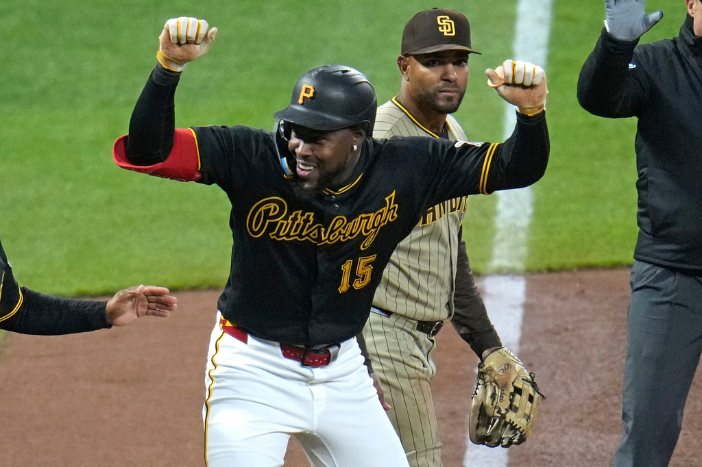 Pittsburgh Pirates' Oneil Cruz (15) celebrates in front of San Diego Padres shortstop Xander Bogaerts as he stands on third base after driving in two runs with a double off pitcher Nick Pivetta during the fifth inning of a baseball game in Pittsburgh, Tuesday, April 7, 2026. (AP Photo/Gene J. Puskar)