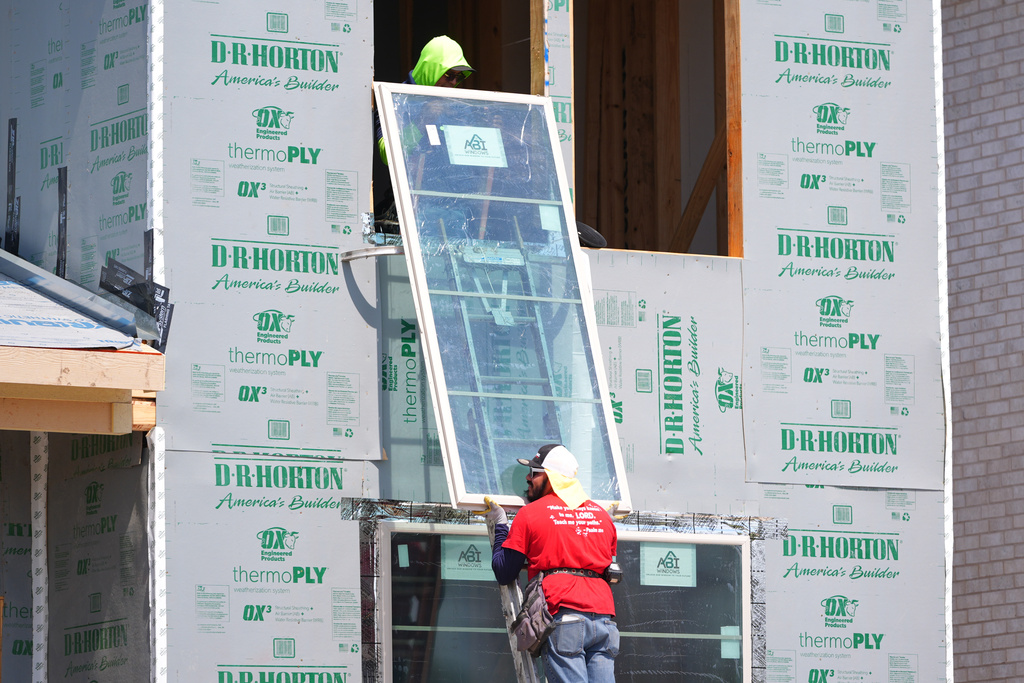 Workers install a window on a house under construction in Richardson, Texas, Monday, March 23, 2026. (AP Photo/LM Otero)