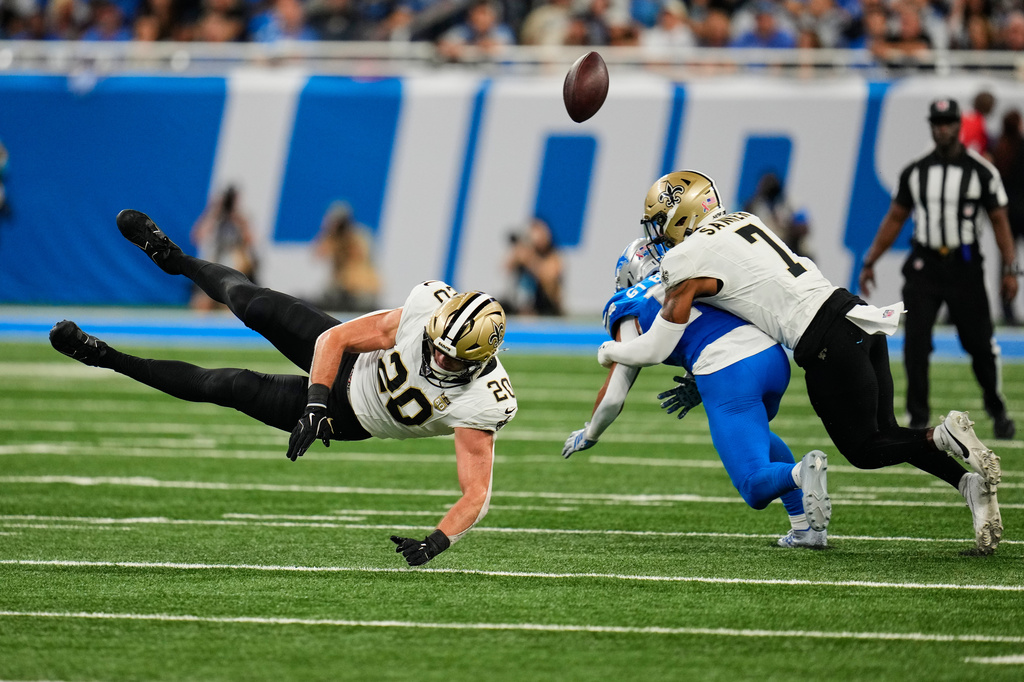 New Orleans Saints linebacker Pete Werner (20) and safety Jonas Sanker (7) break up a pass intended for Detroit Lions wide receiver Amon-Ra St. Brown in the first half of an NFL football game, Sunday, Sept. 13, 2026, in Detroit. (AP Photo/Paul Sancya)