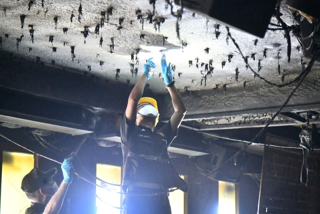 In this handout photo released by Bangkok Metropolitan Administration, forensic police officers inspect the site of a fire in Bangkok, Thailand, Monday, July 13, 2026. (Bangkok Metropolitan Administration via AP)