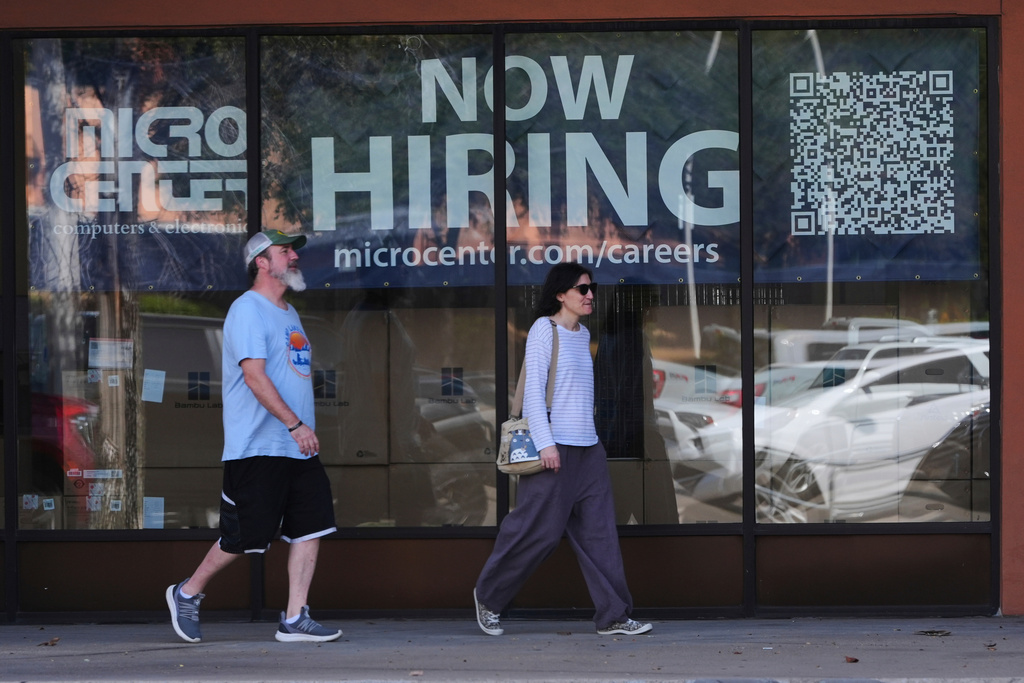 Pedestrians walk by a "Now Hiring" sign at an electronics store in Dallas, Thursday, Aug. 28, 2025. (AP Photo/LM Otero)