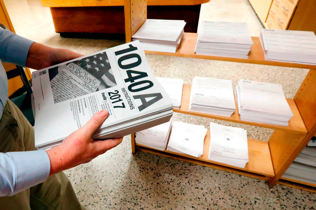 FILE- In this Feb. 15, 2018, photo, Susan Prendergast, reference supervisor at the Eudora Welty Library, in Jackson, Miss., adds additional federal tax filing information booklets on a shelf. (AP Photo/Rogelio V. Solis, File)