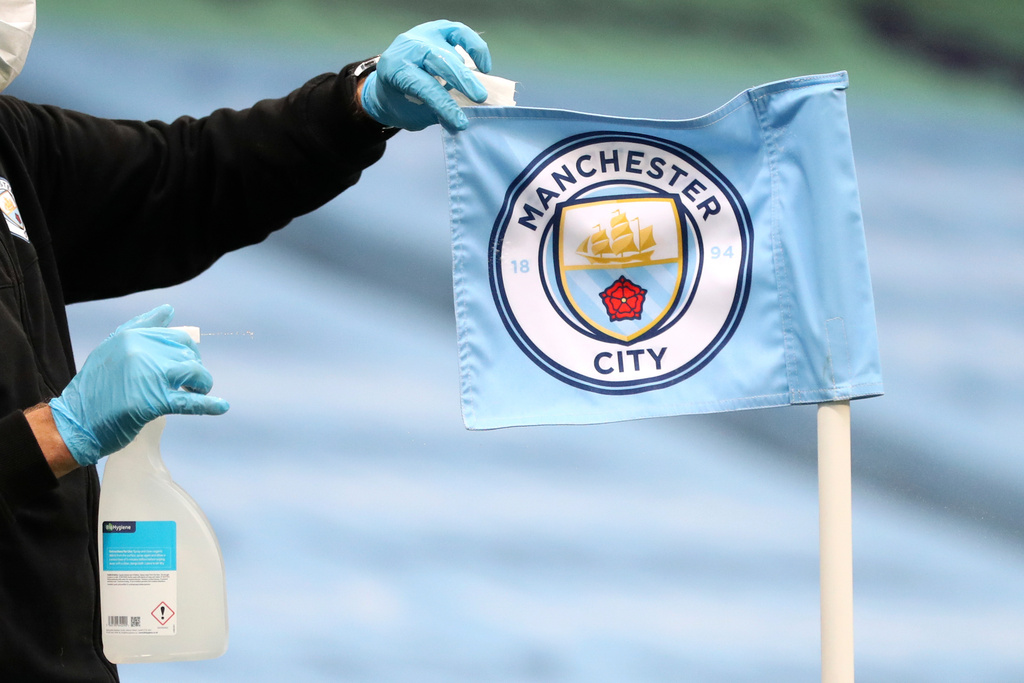 FILE - A groundsman disinfects a corner flag ahead of the English Premier League soccer match between Manchester City and Burnley at Etihad Stadium, in Manchester, England, Monday, June 22, 2020. (AP Photo/Martin Rickett,Pool, File)